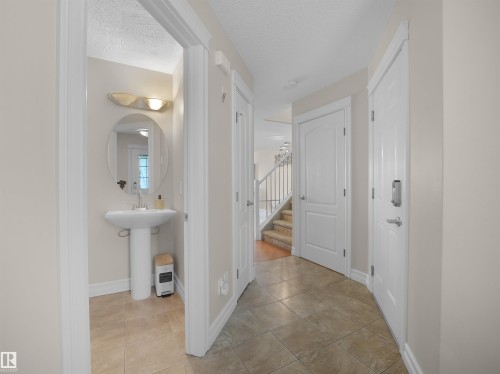 Foyer featuring tile flooring, white interior doors, and a pedestal sink with an oval mirror in the powder room - 17127 126 Street Nw, Edmonton, AB - Indoor Photo Showing Other Room