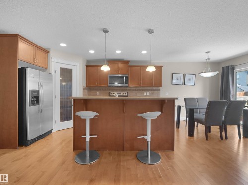 Kitchen with wood-finish flooring, stainless steel refrigerator, built-in microwave, tiled backsplash, and recessed lighting - 17127 126 Street Nw, Edmonton, AB - Indoor Photo Showing Kitchen With Upgraded Kitchen
