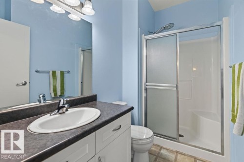 Bathroom featuring a single vanity with an integrated sink, dark-toned countertop, and white cabinetry - #205 4304 139 Av Nw, Edmonton, AB - Indoor Photo Showing Bathroom