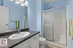 Bathroom featuring a single vanity with an integrated sink, dark-toned countertop, and white cabinetry - 