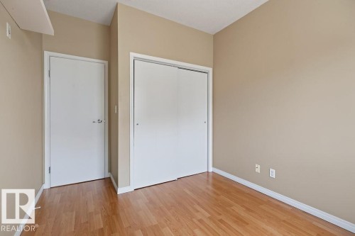 Wood-finish flooring, neutral wall color, white trim, and a white bi-fold closet - #205 4304 139 Av Nw, Edmonton, AB - Indoor Photo Showing Other Room