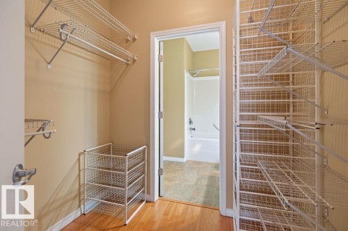 Walk-in closet featuring extensive wire shelving, a built-in wire basket system, and wood-finish flooring - #205 4304 139 Av Nw, Edmonton, AB - Indoor With Storage