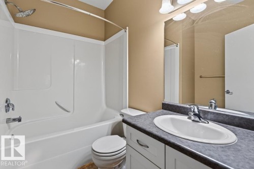 White built-in tub and shower combination with chrome fixtures - #205 4304 139 Av Nw, Edmonton, AB - Indoor Photo Showing Bathroom