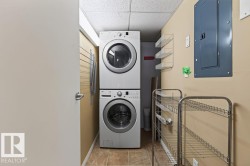 Compact laundry area featuring a stacked washer and dryer, tiled flooring, and neutral wall tones - 