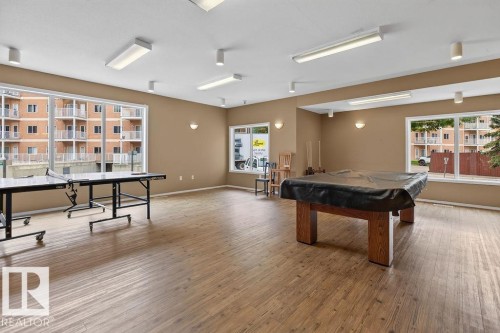 Spacious recreation room featuring wood-finish flooring, ample natural light from large windows, and recessed ceiling lighting - #205 4304 139 Av Nw, Edmonton, AB - Indoor Photo Showing Other Room