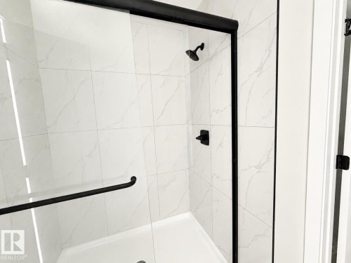 Glass-enclosed shower with matte black hardware, a shower head, and a lever control - 13118 186 Avenue Nw, Edmonton, AB - Indoor Photo Showing Bathroom
