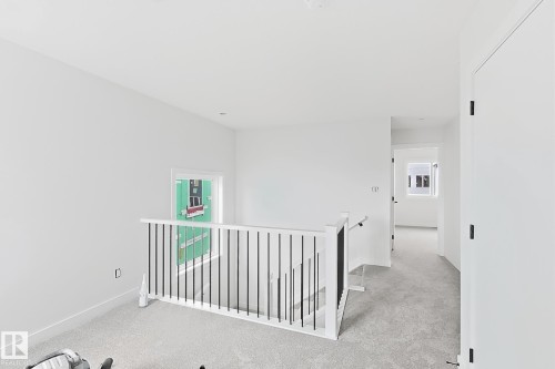 White painted walls, light gray carpet flooring, white painted railing with black spindles, white interior doors with black hardware, and recessed lighting - 13118 186 Avenue Nw, Edmonton, AB - Indoor Photo Showing Other Room