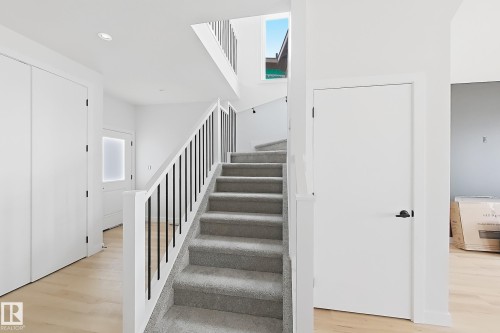 Wood-finish flooring, recessed lighting, white walls, and a staircase with carpeted treads and black metal balusters - 13118 186 Avenue Nw, Edmonton, AB - Indoor Photo Showing Other Room