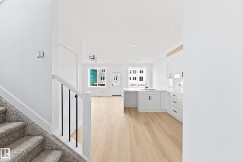 Open-concept design featuring wood-finish flooring, white cabinetry, and a kitchen island with a black faucet - 13118 186 Avenue Nw, Edmonton, AB - Indoor
