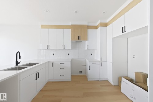 White kitchen cabinetry with matte black hardware, light wood-finish accents, and recessed lighting - 13118 186 Avenue Nw, Edmonton, AB - Indoor Photo Showing Kitchen With Double Sink