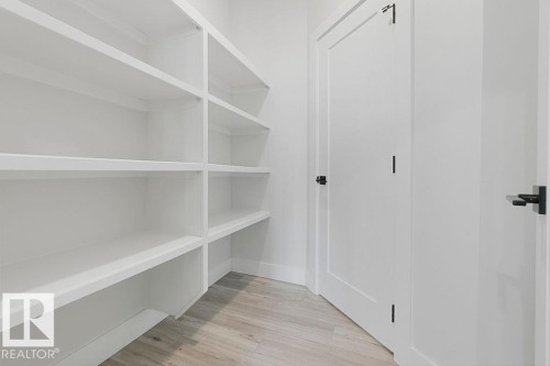 Built-in white shelving, light wood-finish flooring, white paneled doors, and matte black hardware - 9331 181 Avenue Nw, Edmonton, AB - Indoor With Storage