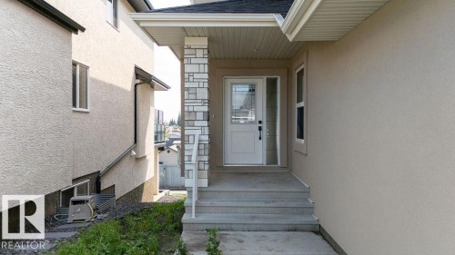 Entryway featuring a decorative stone pillar, concrete steps, and a white door with frosted glass detailing - 9331 181 Avenue Nw, Edmonton, AB - Outdoor