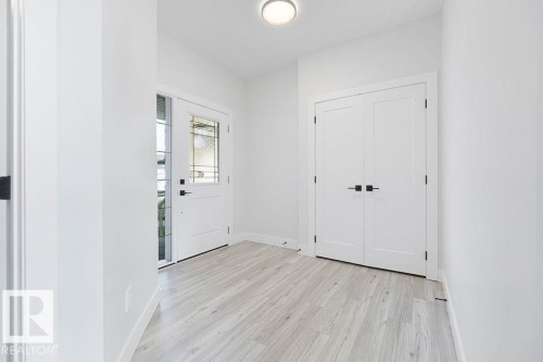 Light wood-finish flooring, white walls, and a ceiling-mounted light fixture illuminate the entry area - 9331 181 Avenue Nw, Edmonton, AB - Indoor Photo Showing Other Room