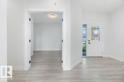 Entryway featuring light wood-finish flooring, white walls, and a white front door with decorative glass inserts - 9331 181 Avenue Nw, Edmonton, AB - Indoor Photo Showing Other Room