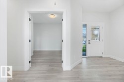 Entryway featuring light wood-finish flooring, white walls, and a white front door with decorative glass inserts - 