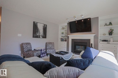 Central fireplace with a dark tile surround and white mantel - 12 Douziech Close, St. Albert, AB - Indoor Photo Showing Living Room With Fireplace