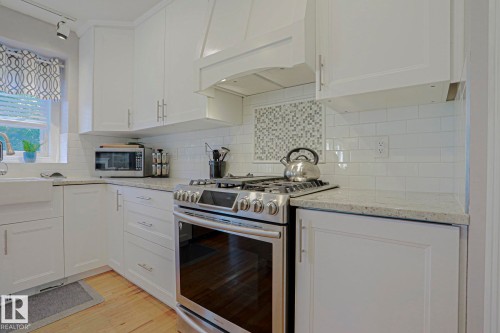 White shaker cabinetry, light-toned countertops, white subway tile backsplash, stainless steel range, and farmhouse-style sink - 12 Douziech Close, St. Albert, AB - Indoor Photo Showing Kitchen With Upgraded Kitchen
