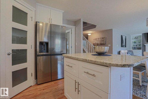 Kitchen island with a light-toned countertop, white cabinetry with silver-toned hardware, and wood-finish flooring - 12 Douziech Close, St. Albert, AB - Indoor Photo Showing Kitchen