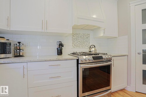 White cabinetry with stainless steel hardware, a white subway tile backsplash, a stainless steel range, and light-toned countertops - 12 Douziech Close, St. Albert, AB - Indoor Photo Showing Kitchen With Upgraded Kitchen
