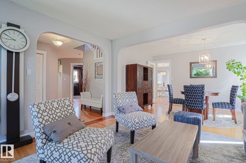 Light-colored walls, wood-finish flooring, arched doorways, white trim, and a contemporary chandelier - 12 Douziech Close, St. Albert, AB - Indoor Photo Showing Other Room