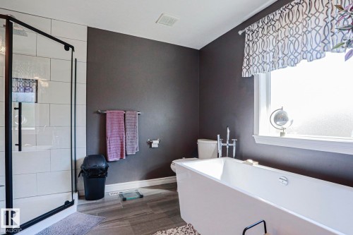 Freestanding soaking tub, glass-enclosed shower with white tiled surround, and a large window with privacy glass - 12 Douziech Close, St. Albert, AB - Indoor Photo Showing Bathroom
