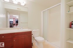 Bathroom featuring a wood-finish vanity, integrated sink, and a shower enclosure with sliding glass doors - 