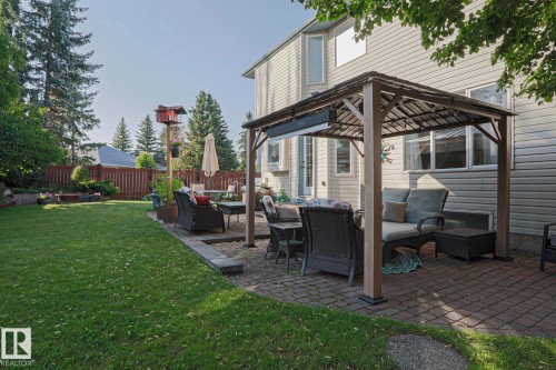 Expansive backyard featuring a large lawn, a paved patio with a gazebo, and privacy fencing - 12 Douziech Close, St. Albert, AB - Outdoor With Deck Patio Veranda With Exterior