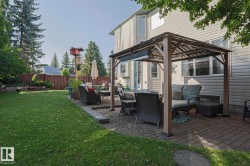 Expansive backyard featuring a large lawn, a paved patio with a gazebo, and privacy fencing - 