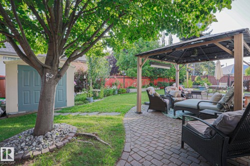 Spacious backyard featuring a paver patio with a gazebo, mature trees, manicured lawn, and a storage shed - 12 Douziech Close, St. Albert, AB - Outdoor With Deck Patio Veranda