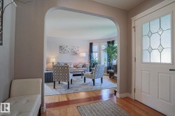 Entryway featuring an arched opening, wood-finish flooring, and a decorative frosted glass paneled door - 