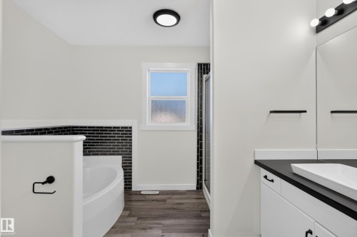 Spacious bathroom featuring a white soaking tub, dark wood-finish flooring, and a walk-in shower with black subway tile - 1315 Westerra Drive, Stony Plain, AB - Indoor Photo Showing Bathroom