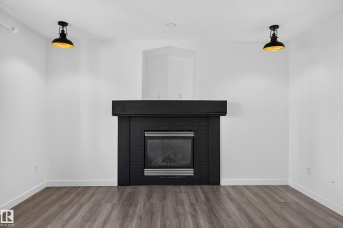 Modern fireplace with a dark surround and mantel, set against white walls - 1315 Westerra Drive, Stony Plain, AB - Indoor Photo Showing Other Room With Fireplace