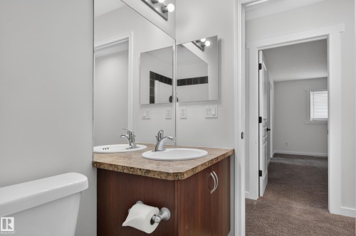 Double vanity with integrated sinks, wood-finish cabinetry, and contemporary lighting - 1315 Westerra Drive, Stony Plain, AB - Indoor Photo Showing Bathroom