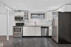 Kitchen featuring white cabinetry, stainless steel appliances, a window, granite-style countertops, and recessed lighting - 