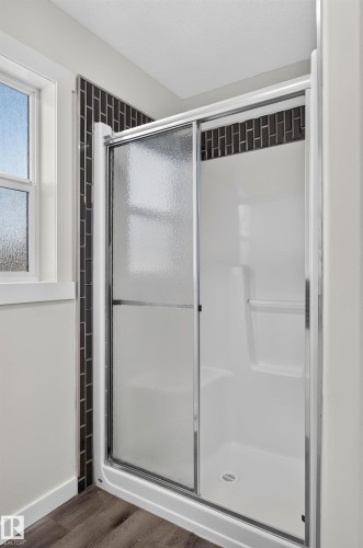 Shower enclosure with sliding glass door, dark subway tile accent, and white fiberglass base - 1315 Westerra Drive, Stony Plain, AB - Indoor Photo Showing Bathroom