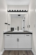 White vanity with dark countertop, vessel sink, and matte black faucet - 