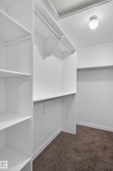 Walk-in closet featuring white shelving, multiple hanging rods, and recessed lighting - 