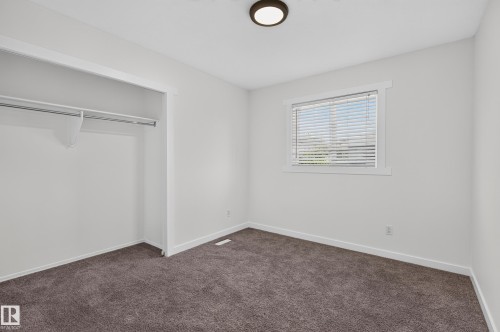 Neutral white walls, plush carpet flooring, recessed closet with hanging rod, flush mount ceiling light, and a window with horizontal blinds - 1315 Westerra Drive, Stony Plain, AB - Indoor Photo Showing Other Room