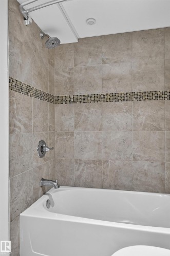 Bathtub with tile surround, mosaic tile accent band, and chrome fixtures - 1315 Westerra Drive, Stony Plain, AB - Indoor Photo Showing Bathroom