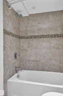 Bathtub with tile surround, mosaic tile accent band, and chrome fixtures - 