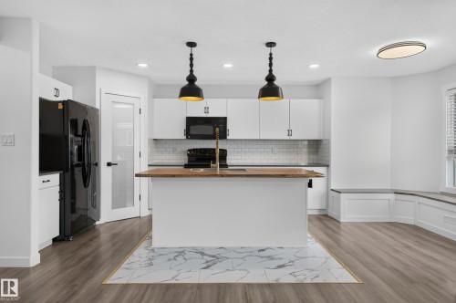 Kitchen featuring a central island with wood-finish countertop, white cabinetry, subway tile backsplash, and black appliances - 1315 Westerra Drive, Stony Plain, AB - Indoor Photo Showing Kitchen
