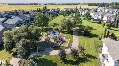 Expansive green space featuring a playground, paved pathways, mature trees, and surrounding residential properties - 1315 Westerra Drive, Stony Plain, AB - Outdoor With View