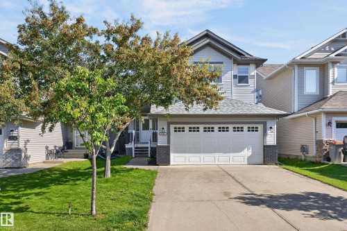 Exterior with light-toned siding and dark trim, featuring a concrete driveway and an attached garage with panel detailing - 1315 Westerra Drive, Stony Plain, AB - Outdoor With Facade