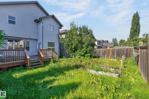 Rear exterior featuring a multi-level wood deck, light gray siding, and a fenced yard with raised garden beds - 1315 Westerra Drive, Stony Plain, AB - Outdoor With Deck Patio Veranda