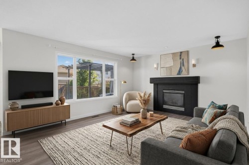 Spacious room featuring wood-finish flooring, a built-in fireplace with a dark mantel, large multi-pane window, and recessed lighting - 1315 Westerra Drive, Stony Plain, AB - Indoor Photo Showing Living Room With Fireplace
