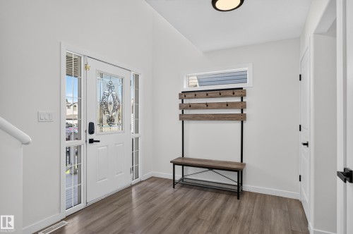 Entryway featuring wood-finish flooring, a decorative glass-paneled entry door with sidelights, and a contemporary flush-mount ceiling light - 1315 Westerra Drive, Stony Plain, AB - Indoor Photo Showing Other Room