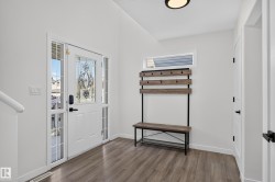 Entryway featuring wood-finish flooring, a decorative glass-paneled entry door with sidelights, and a contemporary flush-mount ceiling light - 
