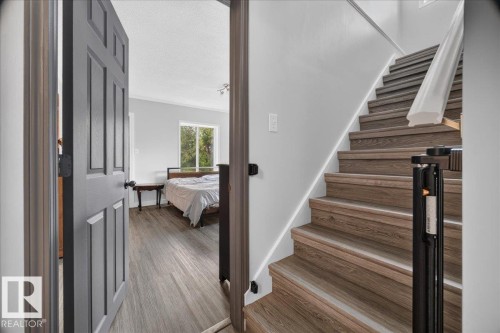 Wood-finish flooring throughout, a paneled door, and a staircase with a white handrail - 543069 Range Road 191, Rural Lamont County, AB - Indoor Photo Showing Other Room