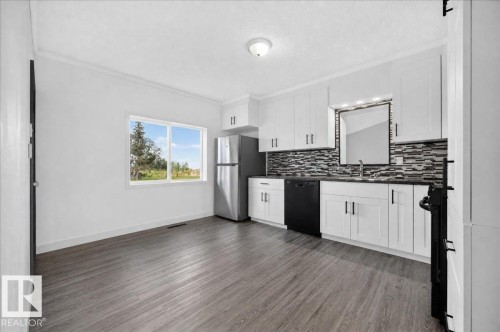 Kitchen featuring white cabinetry, dark countertops, a mosaic tile backsplash, stainless steel appliances, and wood-finish flooring - 543069 Range Road 191, Rural Lamont County, AB - Indoor Photo Showing Kitchen