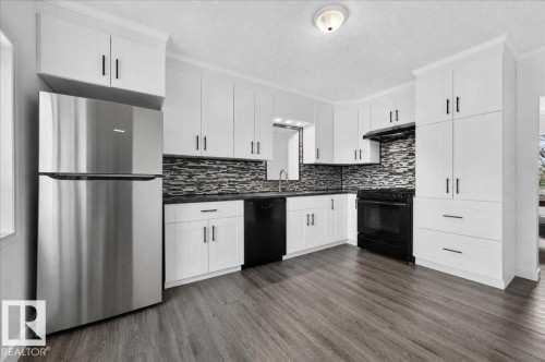 Kitchen featuring white cabinetry, wood-finish flooring, stainless steel refrigerator, black range, and mosaic tile backsplash - 543069 Range Road 191, Rural Lamont County, AB - Indoor Photo Showing Kitchen With Upgraded Kitchen